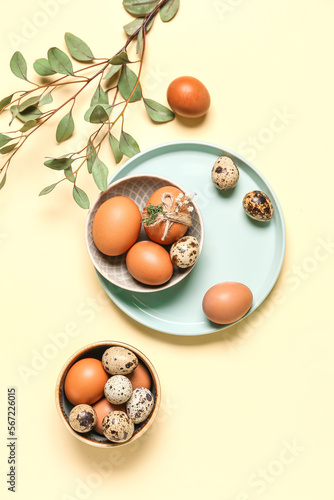Plate and bowl with Easter eggs on yellow background