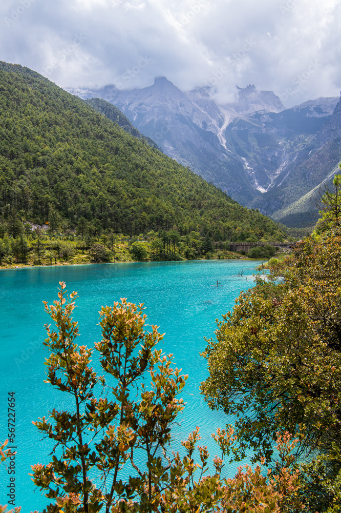 Autumn trees in front of the stunning turquoise lake at the Blue Moon Valley in Lijiang, Sichuan, China, Copy space for text