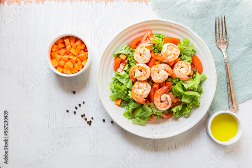 Healthy food shrimp salad lettuce carrot tomato in bowl on wood background.