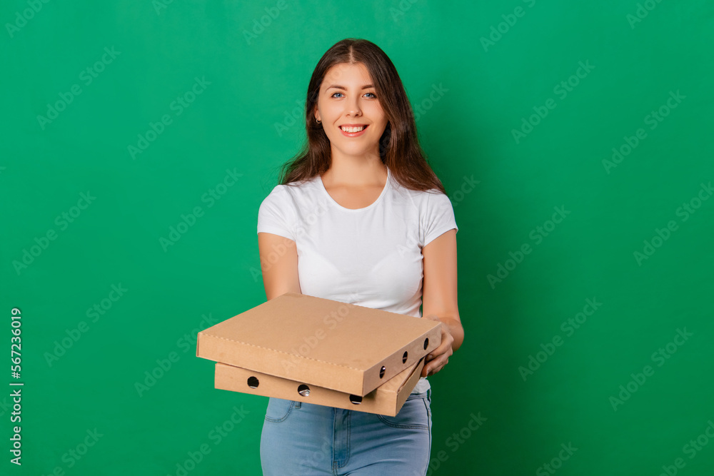 Young woman in a white t-shirt posing with a box of pizza in her hands isolated on a green background. Mockup. Young woman in a white t-shirt posing with a box of pizza in her hands isolated on a green background. Mockup.