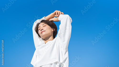 雲ひとつない青空の下で新鮮な空気を吸ってリフレッシュするアジア人女性 photo