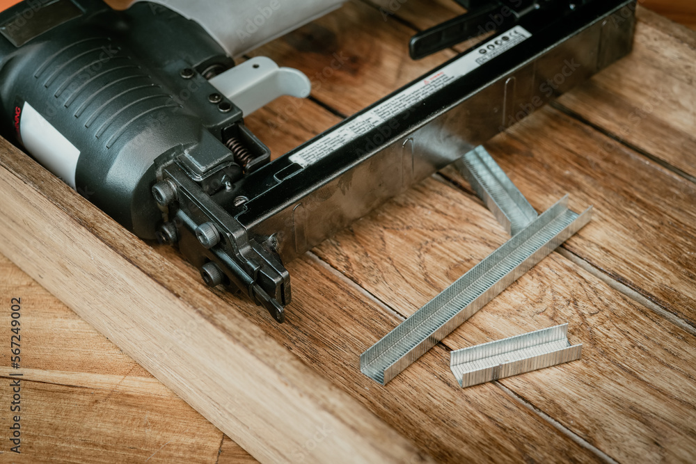 Upholstery Stapler with Staples on wooden desk in workshop. Carpentry Woodworking and DIY Projects concept