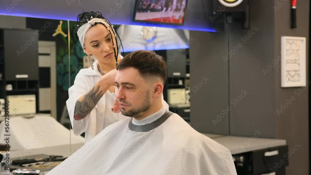 A young stylish female hairdresser cuts men's hair at a beauty center A young stylish female hairdresser cuts men's hair at a beauty center