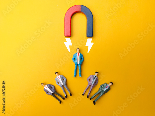 Foto Businessman attracts by magnet on a yellow background