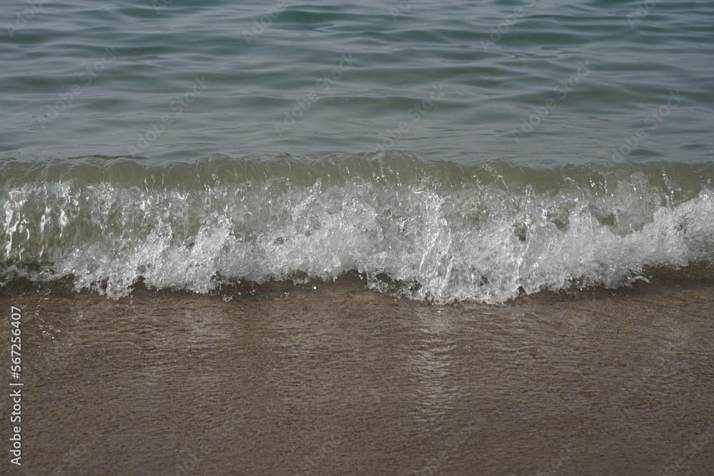 Soft blue ocean wave on clean sandy beach. Selective focus