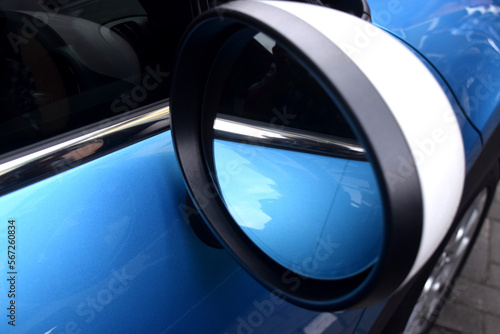 Rearview mirror of a mini cooper car, with a blue painted car as a background