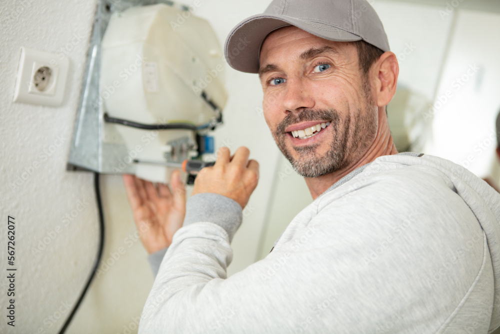 young handyman fixing a kitchen extractor with a screwdriver young handyman fixing a kitchen extractor with a screwdriver