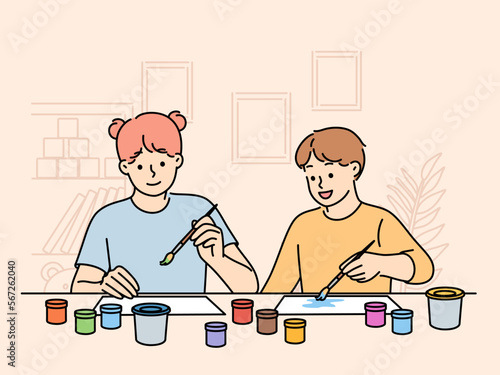 Children sit at table doing joint creativity draw pictures using watercolor or gouache