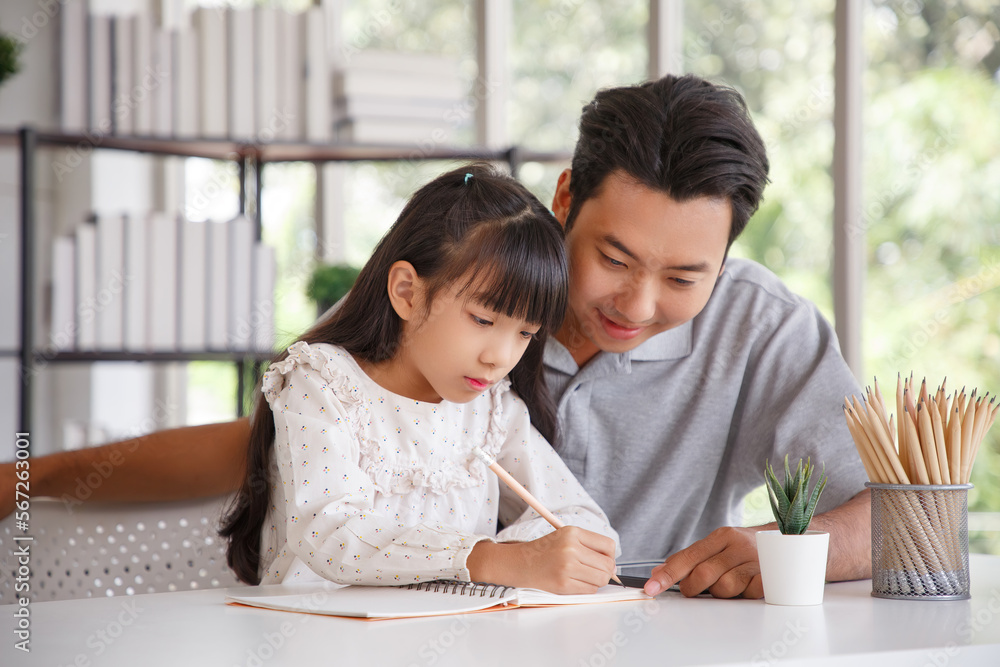 Children education and home school concept : Young asisn father pleased to see little daughters' study success. Excited smiling small child girl enjoying learning and writing with pleasant dad at home Children education and home school concept : Young asisn father pleased to see little daughters' study success. Excited smiling small child girl enjoying learning and writing with pleasant dad at home