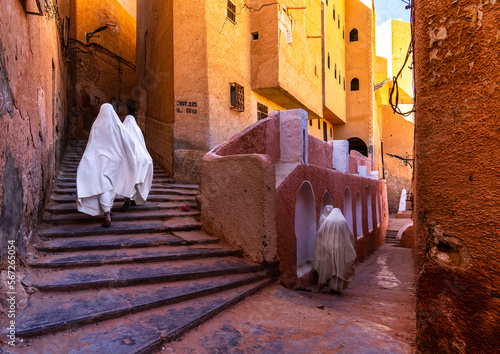 Mozabite women in white haïk in the streets of Ksar El Atteuf, North Africa, Ghardaia, Algeria photo