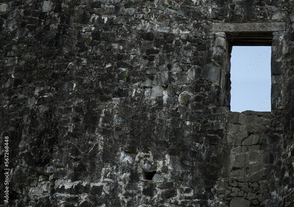 historical background of ruins of an ancient fortress. empty window frame. Ancient window from the ruins of an old castle. grey stone wall backdrop.