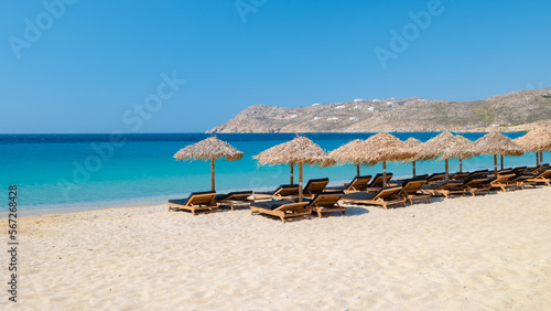 Mykonos beach during summer with umbrella and luxury beach chairs beds, blue ocean at Elia beach