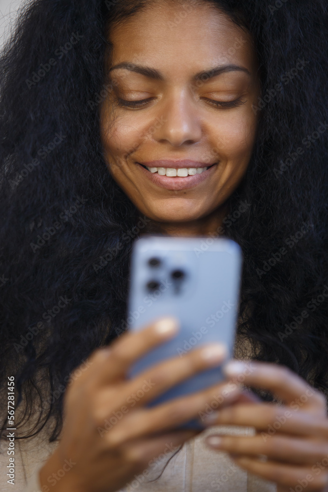Happy black woman using smart phone. Portrait of cheerful BIPOC female in 30s browsing mobile app on a cell phone Happy black woman using smart phone. Portrait of cheerful BIPOC female in 30s browsing mobile app on a cell phone