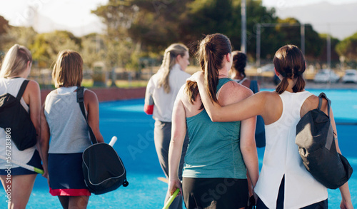Women  hockey and teamwork on field together with support  solidarity or walking to fitness training with coach. Sports group  friends and walk from workout  outdoor exercise or hug with conversation