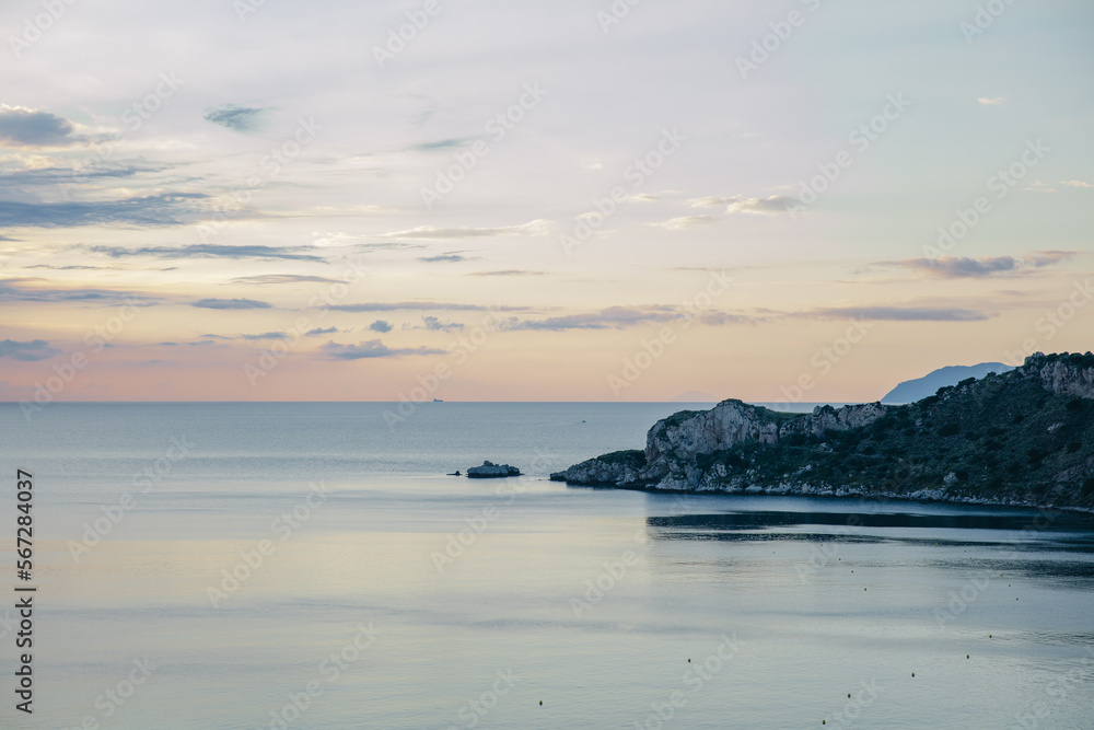 Fototapeta premium rocky seashore overlooking the evening sky in the clouds, the islands in the distance, Sicily, Italy