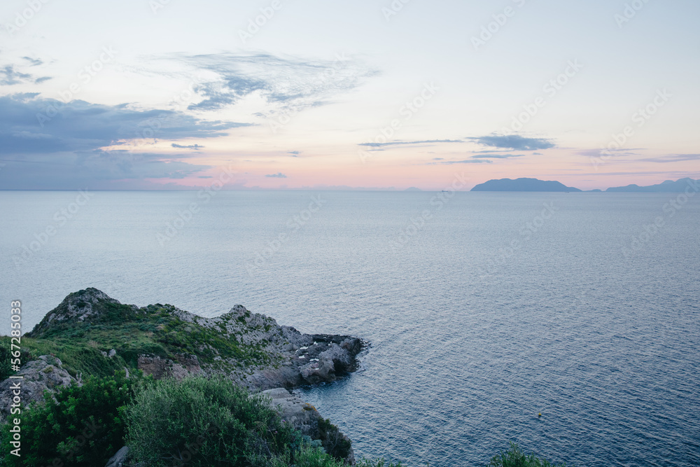 rocky seashore overlooking the evening sky in the clouds, the islands in the distance, Sicily, Italy