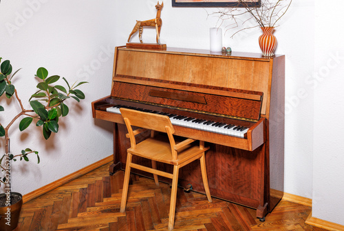 An old piano in the corner of the room against a white wall. photo