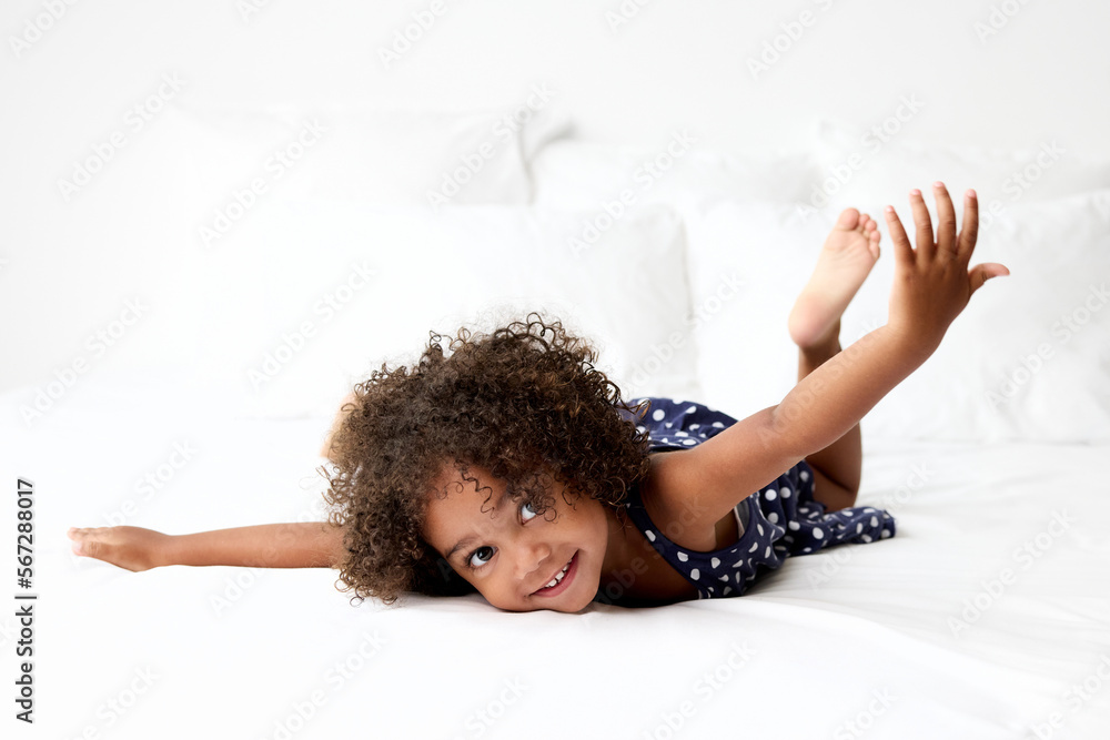 Foto de Smiling little girl with afro hair lying on stomach on white ...