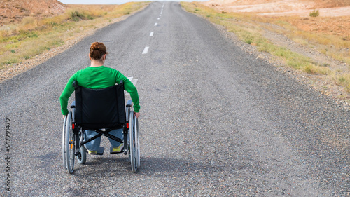 Woman in a wheelchair on a highway in the steppes. 