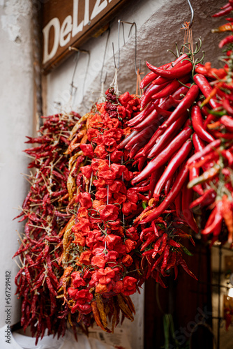 Dried red hot chili peppers hung on the counter at the food market in Italy