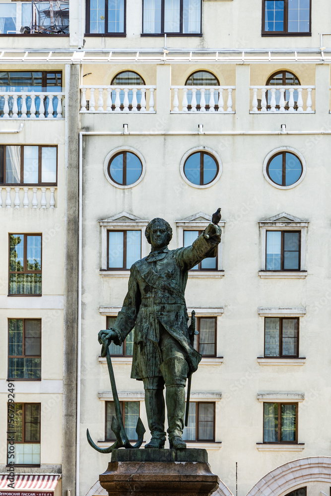 Obraz premium Bronze statue of king is mounted on pedestal made of pink Pavlovsk granite. Monument to Peter I in Petrvsky Square. Ship guns near monument. Fountain in background. Voronezh, Russia - July 30, 2022