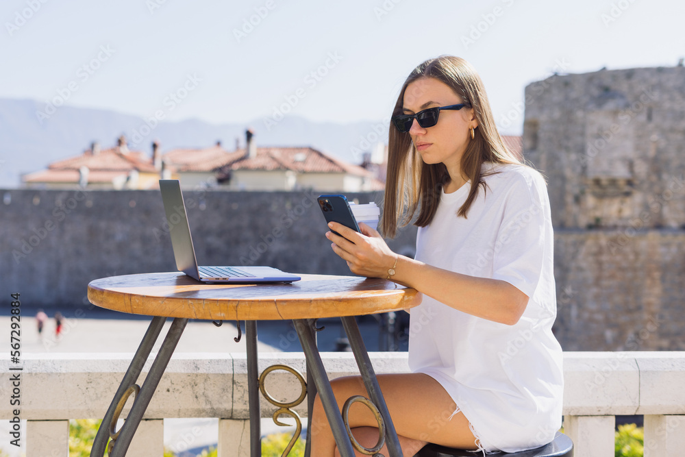 A young woman in a summer cafe. The businesswoman works remotely. Freedom from the office