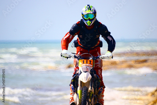 A motorcyclist on an enduro motorcycle rides along the seashore	
