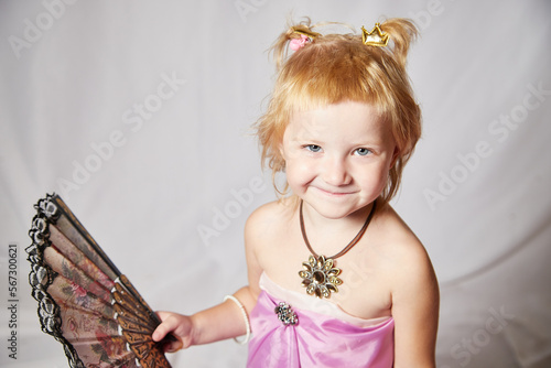 Portrait of cute kid girl posing in pink beautiful dress on a white background. Young female model looking as magic princess from fairy taly photo