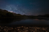 Milky way over Mae Pha Haen Reservoir with mountain view at night. On Tai, San Kamphaeng District, Chiang Mai. Thailand.