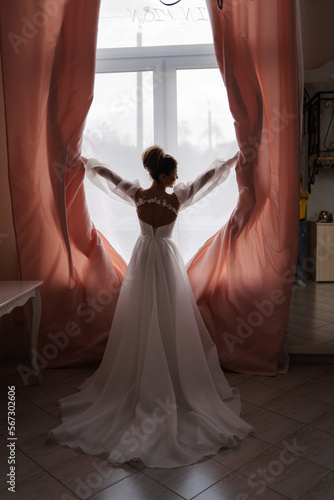young bride opens window curtains