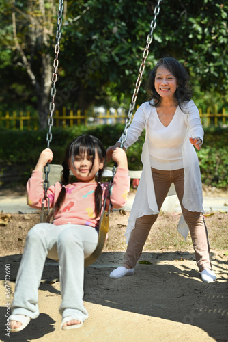 Joyful little girl having fun on swing with grandmother, spending weekend time together. Generational, family and love concept © Prathankarnpap