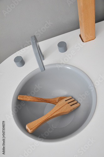 Furniture and toys for children. Wooden play sink with wooden spoon and fork. Baby independence and helping mom, Montessori kindergarten. Happy childhood