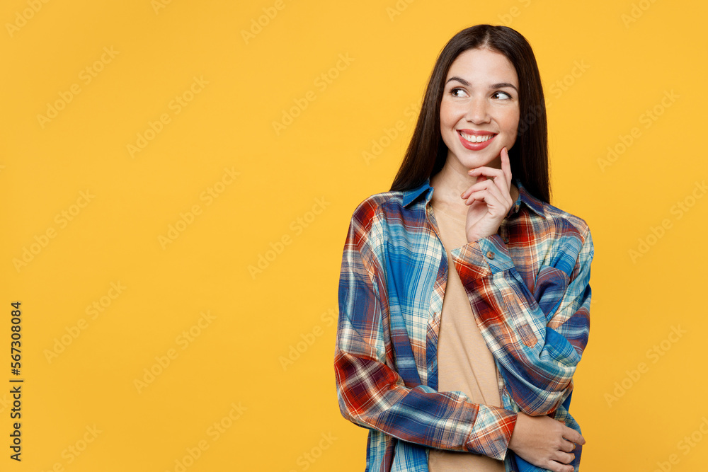 Young fun woman wear blue shirt beige t-shirt put hand prop up on chin, lost in thought and conjectures look aside on area isolated on plain yellow background studio portrait People lifestyle concept Young fun woman wear blue shirt beige t-shirt put hand prop up on chin, lost in thought and conjectures look aside on area isolated on plain yellow background studio portrait People lifestyle concept