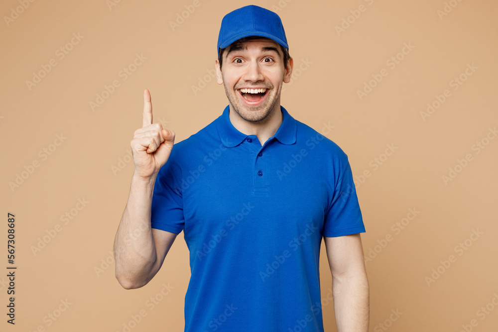 Professional delivery guy employee man wear blue cap t-shirt uniform workwear work as dealer courier hold index finger up with great new idea isolated on plain light beige background. Service concept. Professional delivery guy employee man wear blue cap t-shirt uniform workwear work as dealer courier hold index finger up with great new idea isolated on plain light beige background. Service concept.
