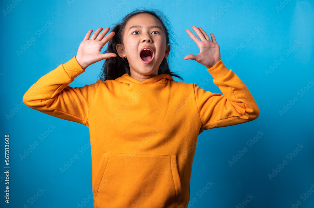 the studio isolated a portrait image of the acting of a happy girl with a blue backdrop. the studio isolated a portrait image of the acting of a happy girl with a blue backdrop.