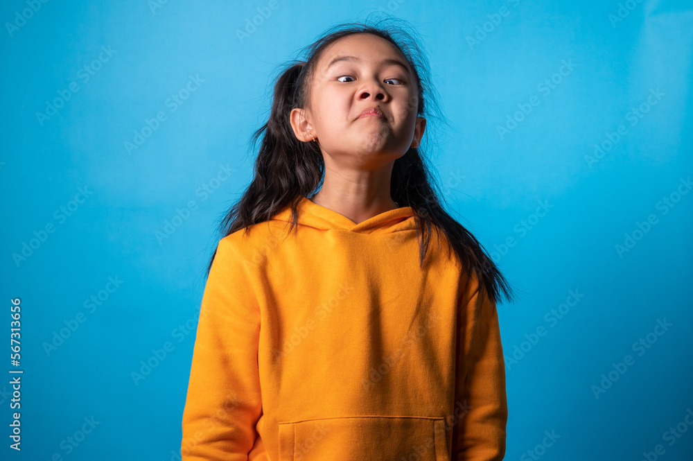 Fototapeta premium the studio isolated a portrait image of the acting of a happy girl with a blue backdrop.