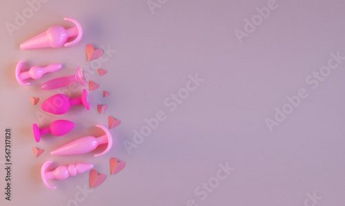 Pink silicone sex toys and paper heart on a pink background. the concept of valentine s day  love. Erotic toy for fun. Diffrent anal butt plugs. Banner with space for text