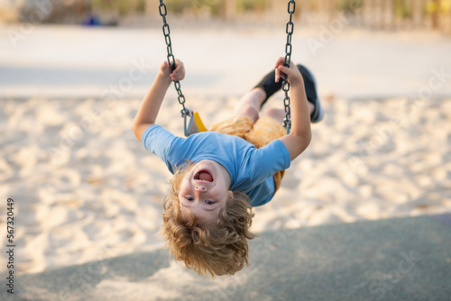 Swinging on playground. Happy child enjoy swinging. Kid swinging. Happy little child having fun on swing in playground. Cute child swinging on sunny spring day. photo