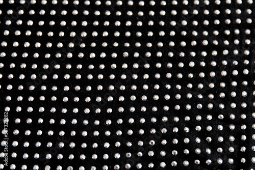 Black cotton folded fabric with dotted metal rivets as background