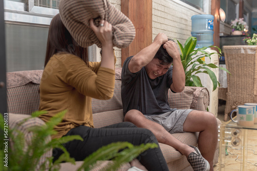 Принти на полотні An asian couple having a fun pillow fight while sitting in the couch at the living room