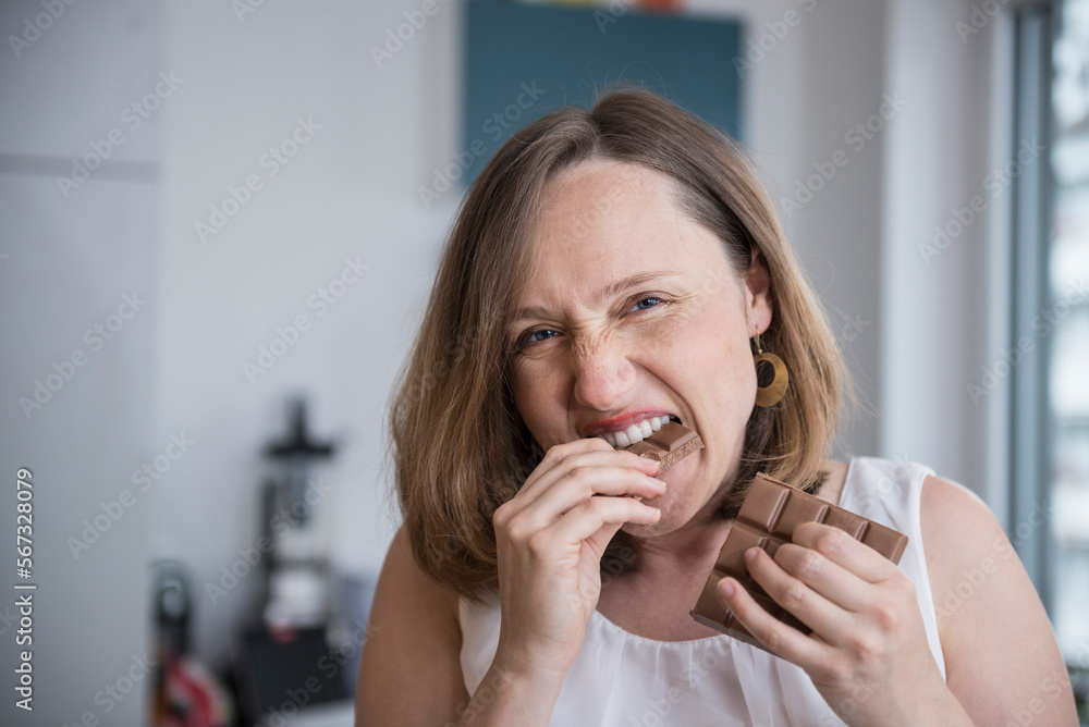 Portrait of a pregnant woman eating chocolates in the kitchen, Munich, Bavaria, Germany Portrait of a pregnant woman eating chocolates in the kitchen, Munich, Bavaria, Germany