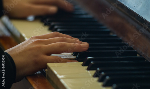 Two hands on the piano keys. A child plays the piano. The musician plays the piano. Close to the musician's hands