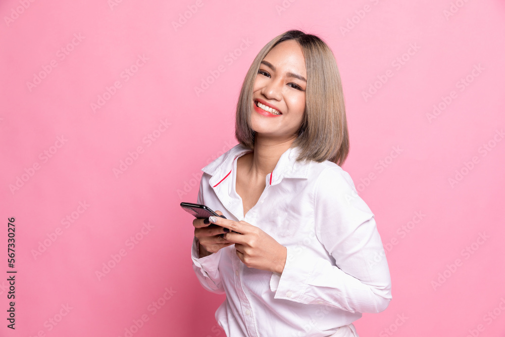 Smiling lovely young woman standing and using cell phone over pink background. Smiling lovely young woman standing and using cell phone over pink background.