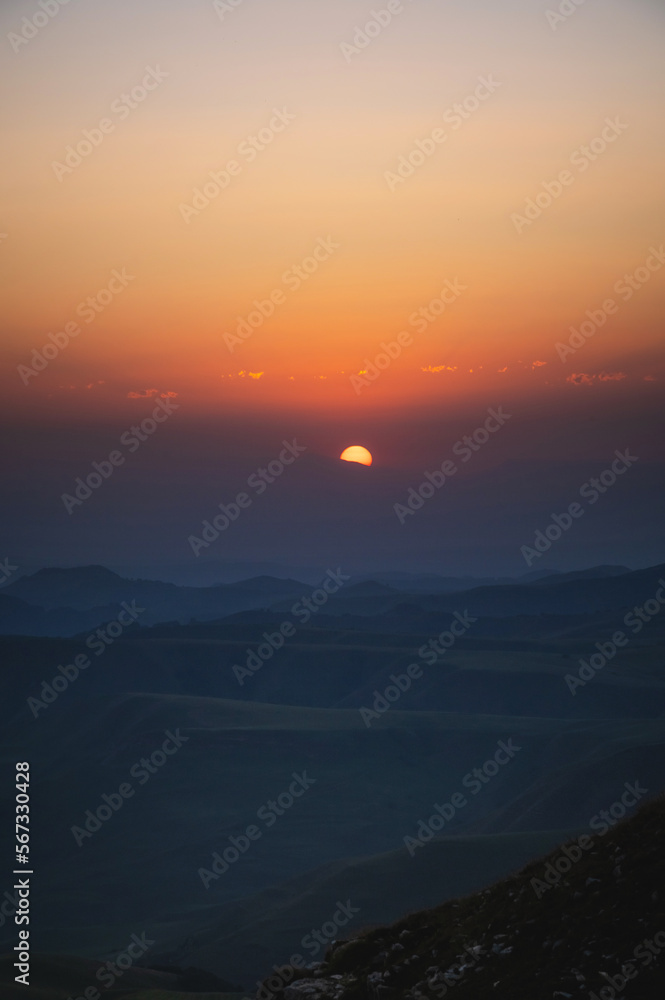 Beautiful mountain landscape with sunset over the mountains from the top of the mountain. Photo in orange-blue natural tones