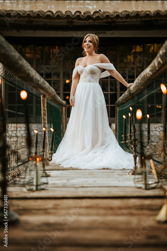 Beautiful bride posing on wooden bridge full of candles