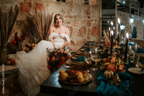 Beautiful bride by wedding table, richly decorated in rustic style © eunikas