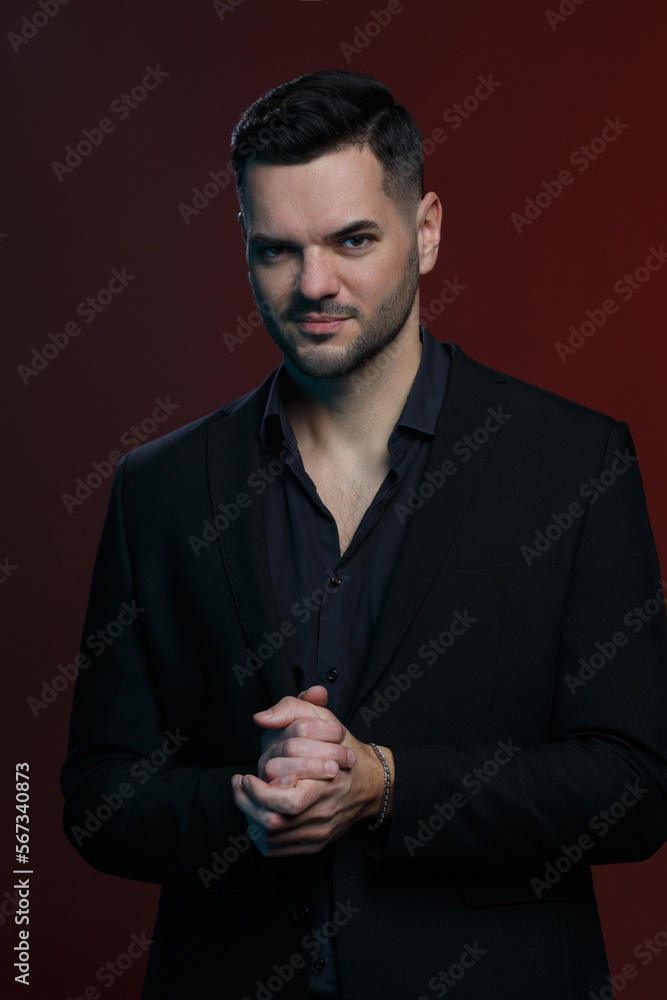 Attractive man in an elegant black suit  on a dark burgundy background.