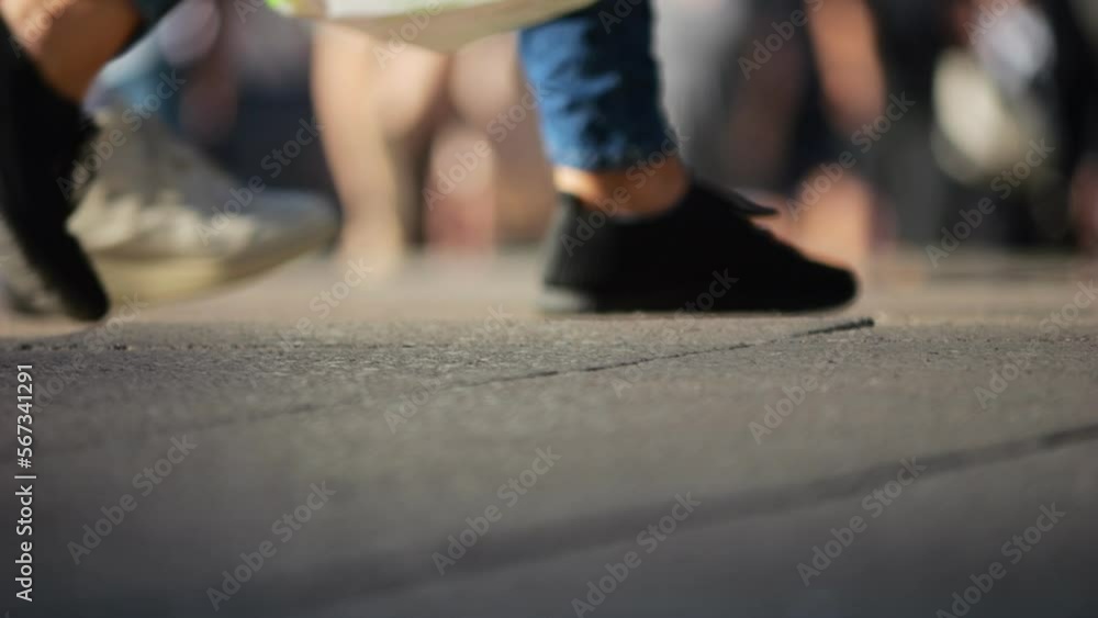Legs of a crowd of people walking down the street, close-up of people's feet. Slow motion. Many feet walk on the pavement. Low view of crowded people walking in the square. Urban crowd. Legs of a crowd of people walking down the street, close-up of people's feet. Slow motion. Many feet walk on the pavement. Low view of crowded people walking in the square. Urban crowd.