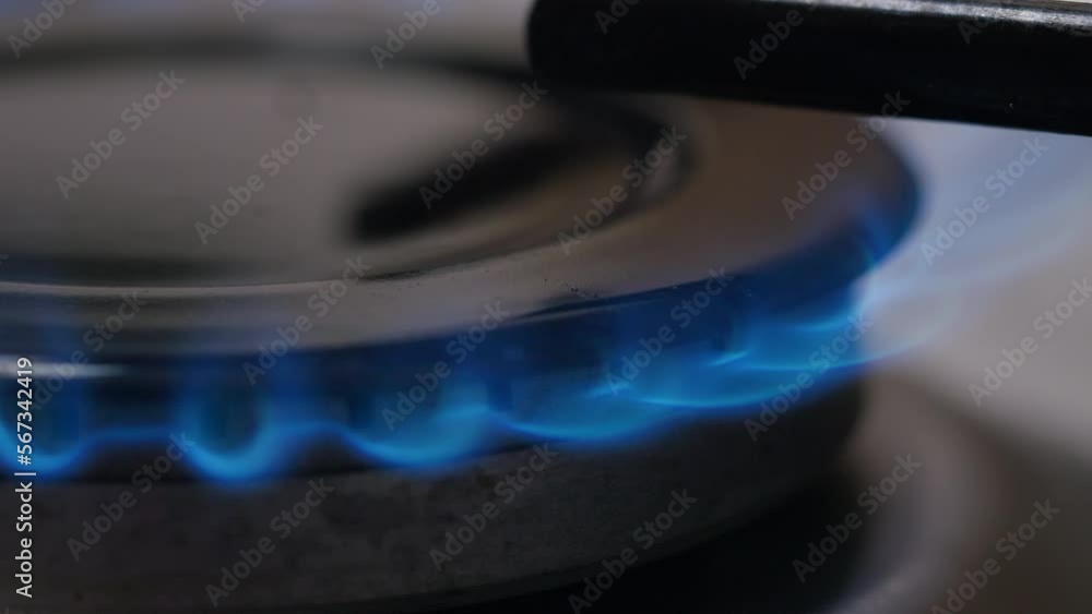 Stove top burner igniting into a blue cooking flame side view. Kitchen