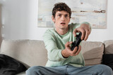 KYIV, UKRAINE - OCTOBER 24, 2022: cheerful young man in sweatshirt playing video game at home